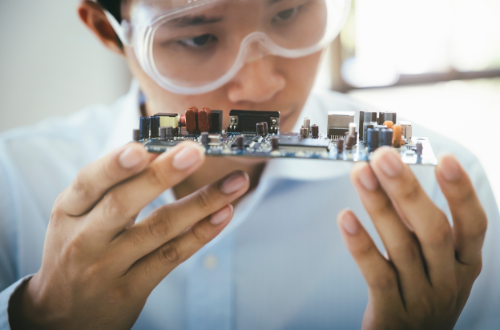 Engineer inspecting assembled PCB representing custom electronics design and hardware validation